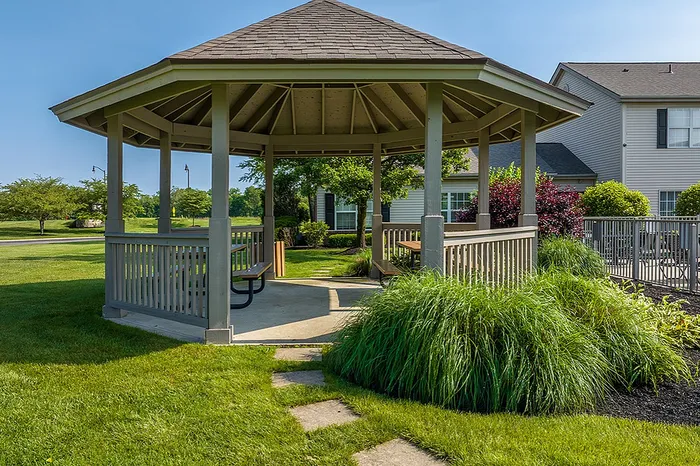 Charming outdoor gazebo nestled in lush greenery, perfect for relaxation and gatherings in a serene neighborhood setting.