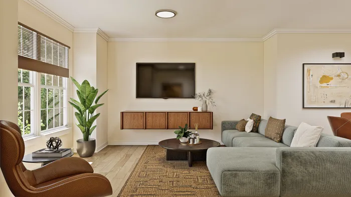Inviting living room with a chic modern design, featuring a plush sectional sofa, mounted TV, and large window with abundant natural light.