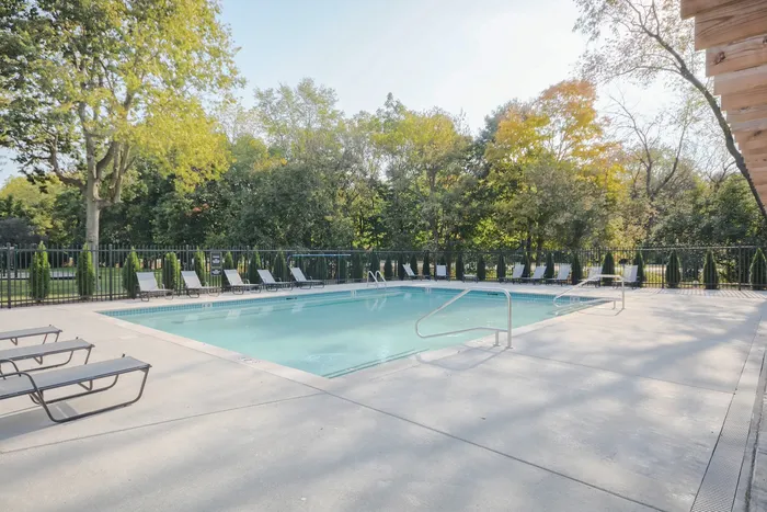 Inviting outdoor swimming pool with surrounding lounge chairs, lush greenery, and serene ambiance perfect for relaxation.