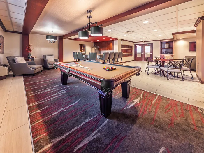 Elegant game room with a stylish pool table, cozy seating, and modern lighting, perfect for entertainment and relaxation.