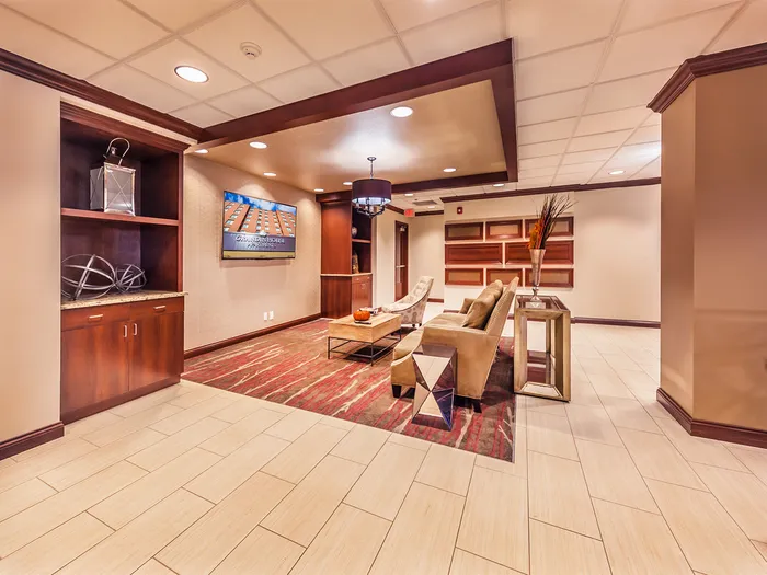 Elegant apartment lobby with modern decor, featuring a cozy seating area, sleek wooden shelving, and stylish lighting.