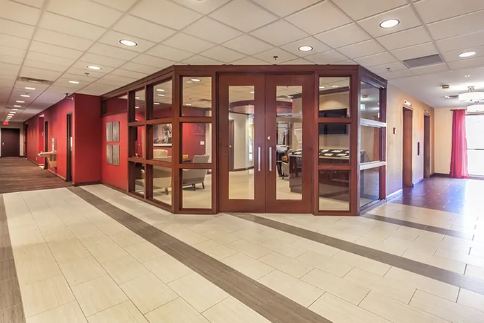 Modern apartment lobby featuring elegant glass and wood accents, spacious seating area, and vibrant red walls.