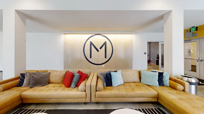 MARQ apartments resident lounge featuring luxurious leather sofas with colorful pillows and stylish wall decor.