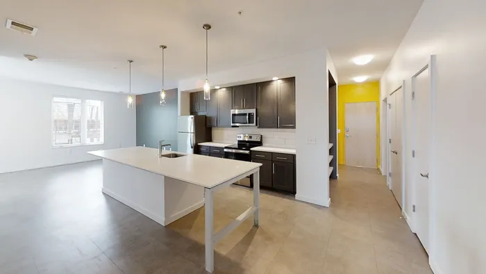 MARQ modern apartment kitchen with sleek dark cabinetry, stainless steel appliances, and a spacious island with pendant lighting.
