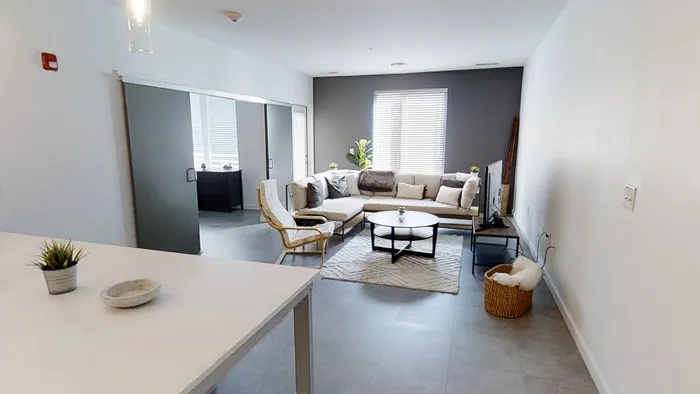 Contemporary open-concept living room featuring elegant sectional sofa, modern armchair, and sleek decor with abundant natural light.