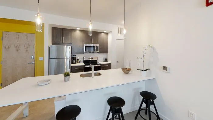 MARQ modern kitchen with sleek dark cabinetry, stainless steel appliances, and a stylish breakfast bar with pendant lighting.
