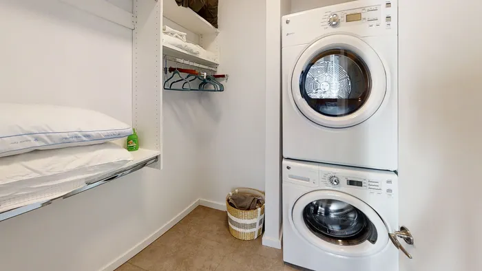 MARQ modern laundry room with stacked washer and dryer, built-in shelving, and organized hanging space.