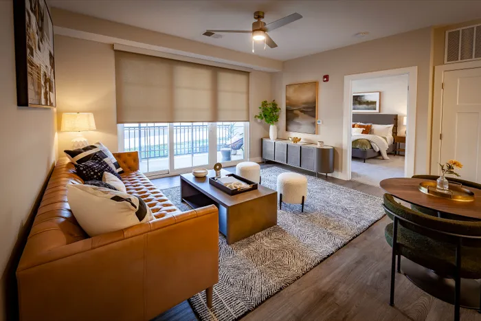 Elegant living room with a chic leather sofa, modern decor, and abundant natural light, connected to a cozy bedroom.