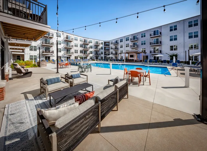 Modern apartment complex featuring luxurious poolside lounge area with comfortable seating and vibrant outdoor dining spaces.