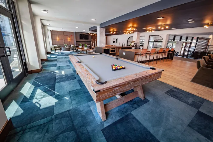 Luxurious apartment lounge featuring a modern billiards table, stylish seating, and a sleek, spacious bar area.