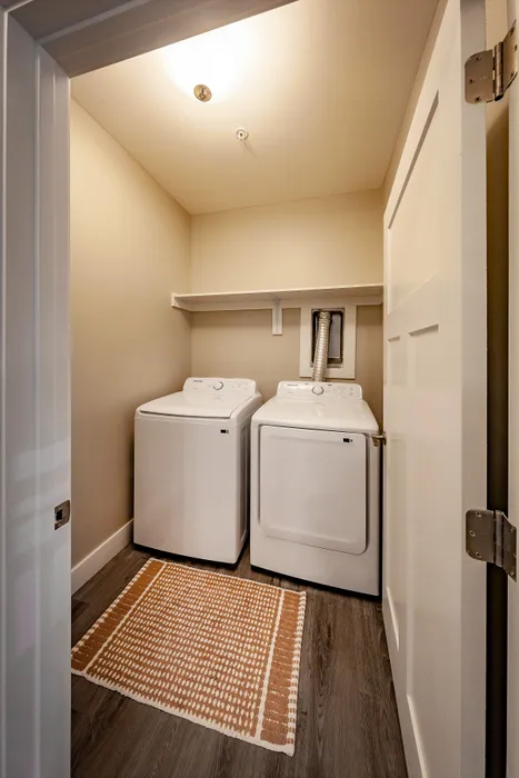 Modern laundry room featuring energy-efficient washer and dryer with ample shelving and stylish flooring.