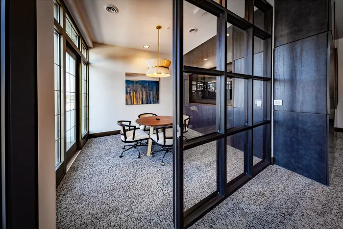 Chic, sunlit modern office space with glass walls, elegant lighting, and tasteful artwork.
