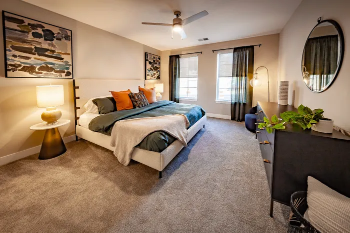 Elegant bedroom with plush carpeting, stylish decor, and large windows providing abundant natural light.