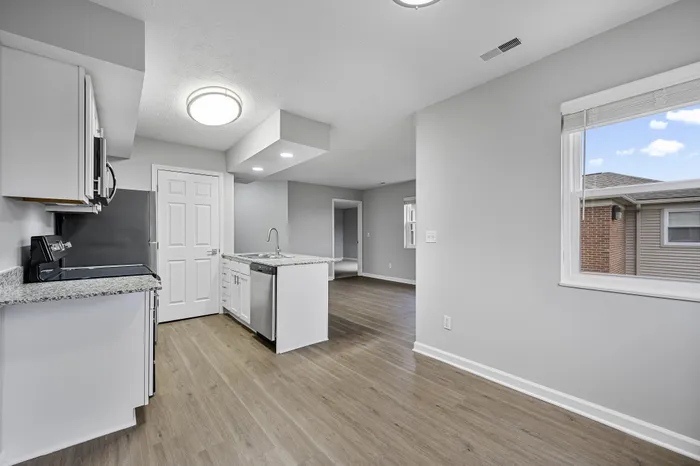 Modern open-plan kitchen with sleek gray cabinetry, stainless steel appliances, and bright natural lighting.