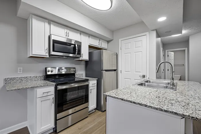 Modern kitchen with sleek stainless steel appliances, granite countertops, and elegant white cabinetry.