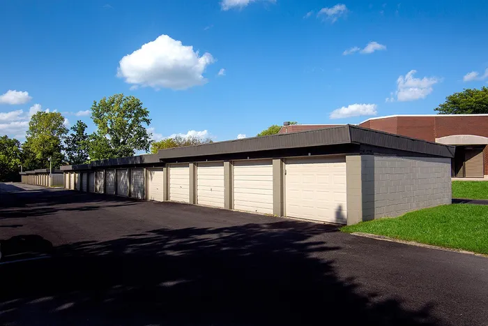 Modern storage garages with sleek design, surrounded by lush greenery, under a bright blue sky.