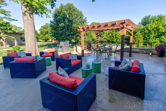 Inviting outdoor lounge area with modern patio furniture, vibrant cushions, and pergola, perfect for gatherings and relaxation in a lush green setting.