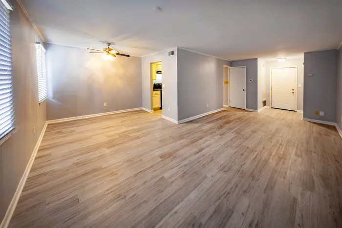 Elegant and spacious living area with modern wood flooring, ambient lighting, and accessible kitchen entry.