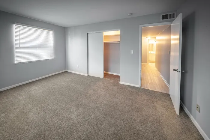Bright and spacious bedroom featuring plush carpeting, ample closet space, and a modern en-suite bathroom.
