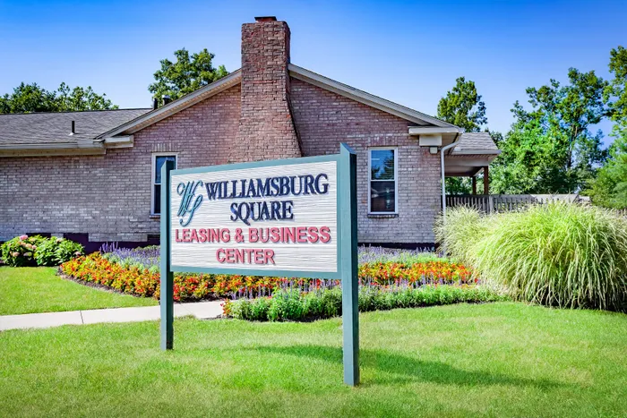 Charming Williamsburg Square Leasing Center surrounded by lush greenery and vibrant flower beds, offering a welcoming and serene environment.