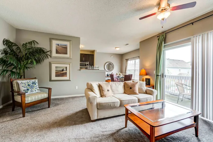 Inviting living room with plush sofa, elegant coffee table, and open-concept layout featuring a dining area and access to a sunny balcony.