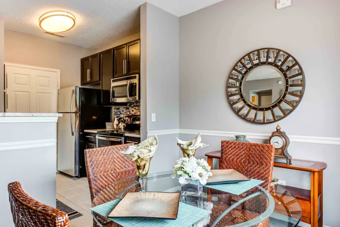 Charming dining area with wicker chairs, elegant glass table, and modern kitchen featuring stainless steel appliances.