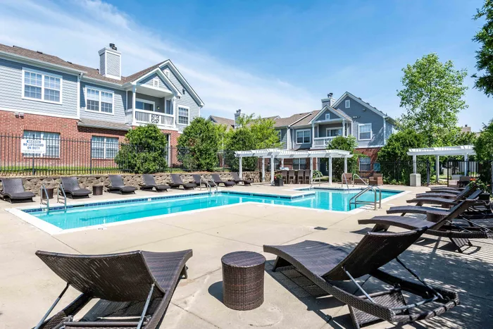 Luxurious outdoor pool area with stylish lounge chairs, surrounded by lush greenery, perfect for relaxation and leisure.