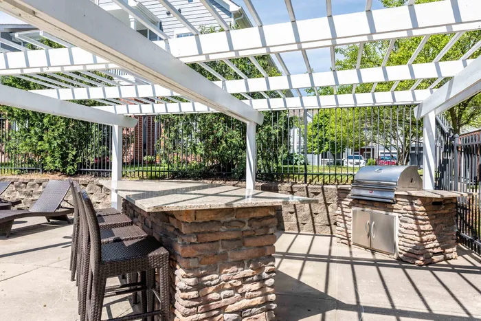 Beautiful outdoor patio with modern grill, stylish stone countertops, and shaded dining area perfect for entertaining.