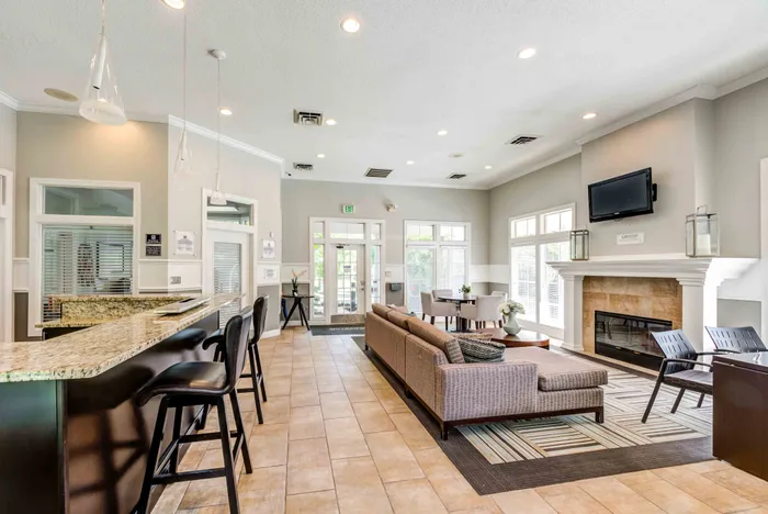 Inviting and spacious clubhouse with a cozy fireplace, modern furnishings, high ceilings, and ample natural light, perfect for relaxation.