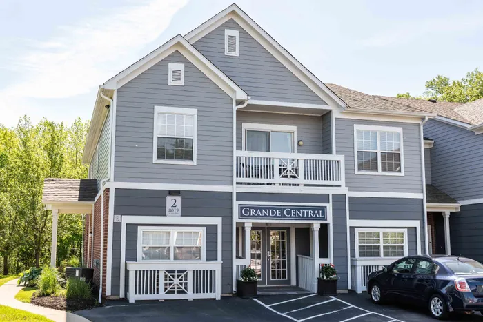 Charming leasing office with a welcoming entrance at Grande Reserve at Geist, surrounded by lush greenery.