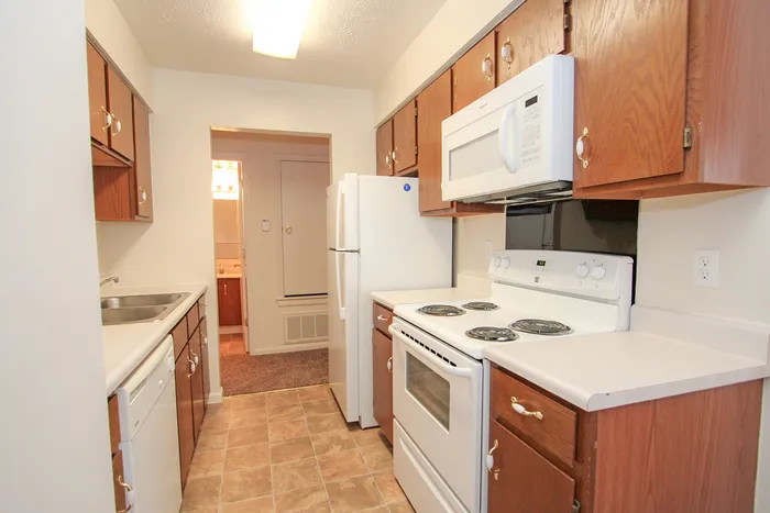 Charming kitchen with sleek white appliances, wood cabinetry, and a cozy layout.