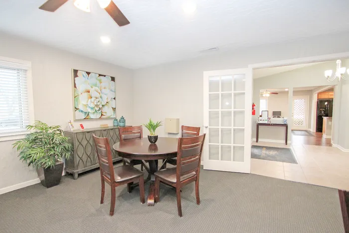 Inviting clubhouse dining and lounge area featuring warm wood furnishings and stylish d&eacute;cor, opening into a bright, spacious community gathering space.