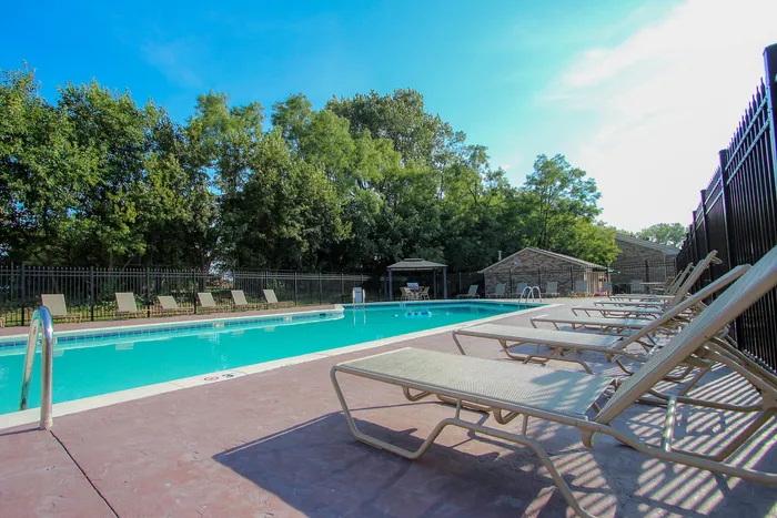 Inviting outdoor pool area with rows of sun loungers, surrounded by lush greenery.