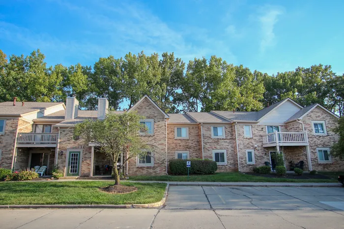 Charming brick apartment building with cozy balconies and lush green surroundings.