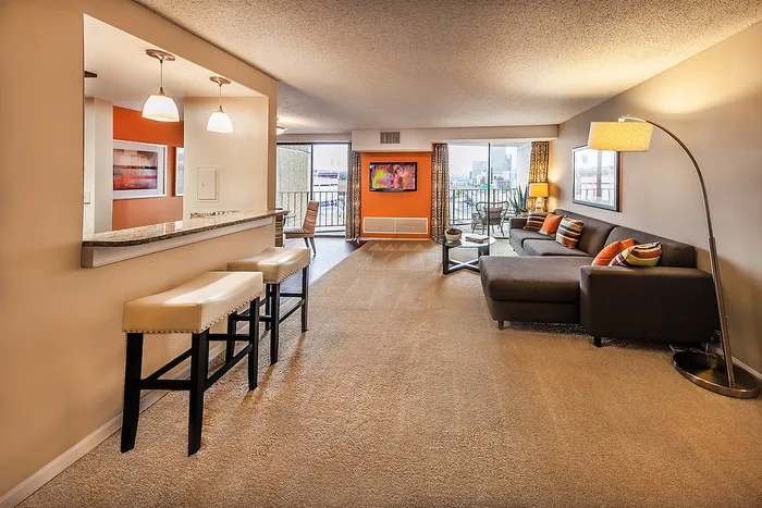Modern living room with chic decor, plush seating, and vibrant accent wall, featuring a breakfast bar and panoramic city view.