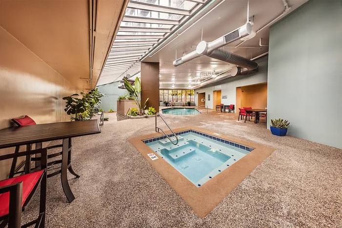Luxurious indoor pool area with a relaxing hot tub, stylish seating and expansive skylights.