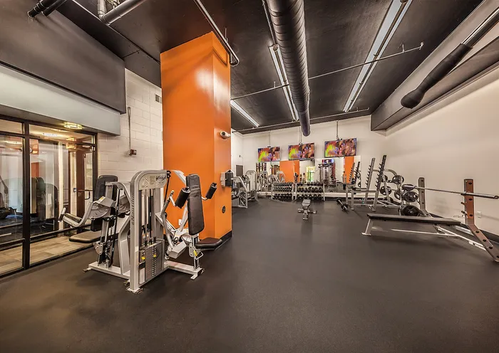 Modern fitness center with state-of-the-art exercise equipment, vibrant orange accents, and an inviting workout ambiance.