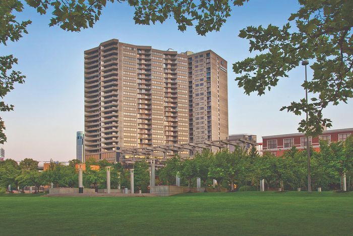 Impressive high-rise apartment building surrounded by lush green parkland, ideal for urban living enthusiasts seeking modern convenience mixed with natural beauty.