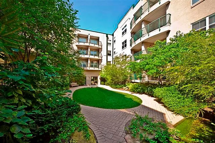 Serene apartment courtyard with lush greenery, manicured lawn, and modern balconies offering a peaceful urban retreat.