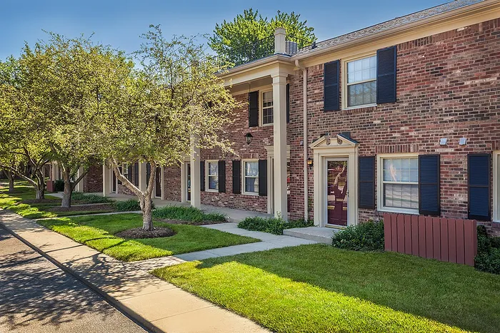 Charming red-brick apartment building with classic architecture, surrounded by lush greenery and mature trees for a peaceful living experience.