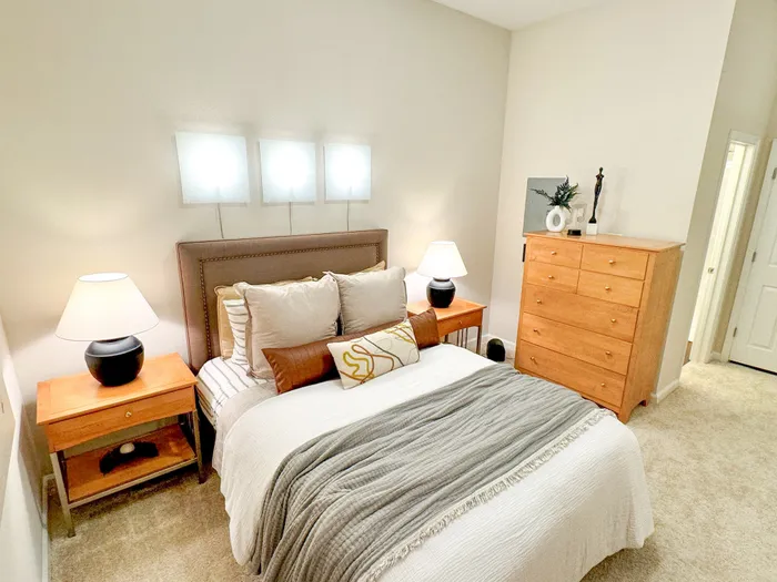 Inviting bedroom with plush bedding, elegant wooden furniture, and soft ambient lighting creates a cozy retreat.