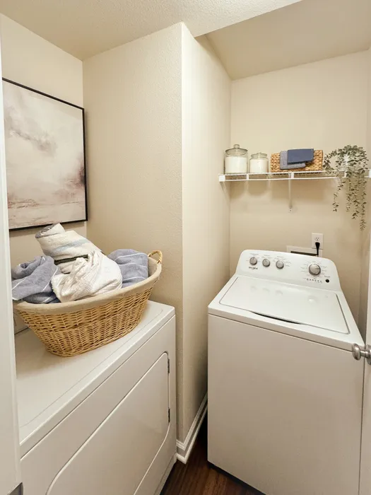 Charming laundry nook with modern washer and dryer, stylish shelving, and elegant decor for a cozy and efficient space.