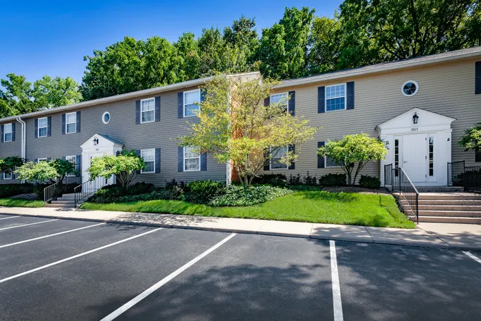 Charming apartment exterior with lush landscaping and ample parking, offering a warm community feel.