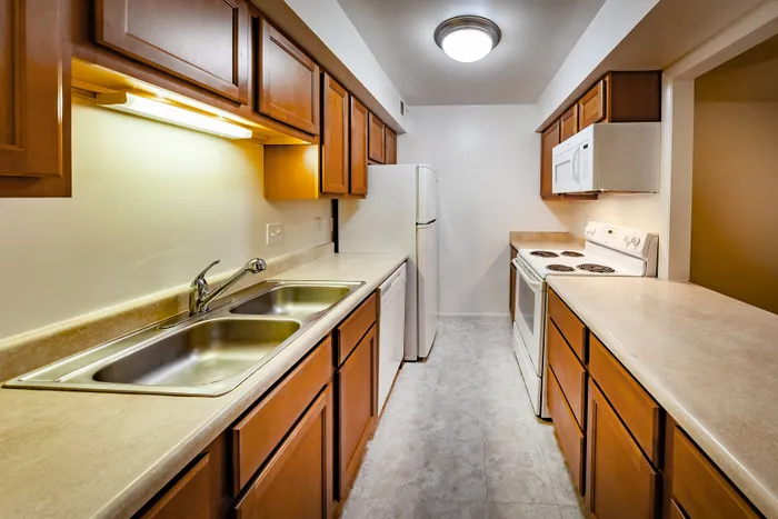 Charming galley-style kitchen with warm wooden cabinetry, sleek countertops, and modern appliances, perfect for culinary enthusiasts.