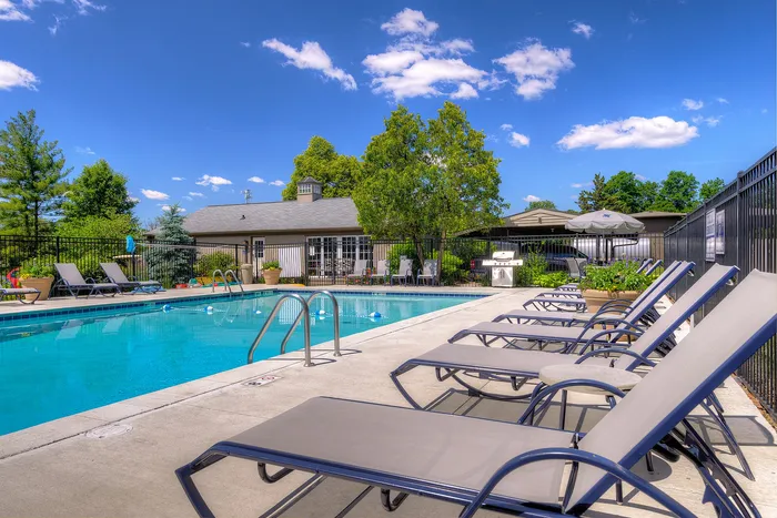 Inviting outdoor pool area with comfortable lounge chairs and lush greenery, perfect for relaxation and leisure.