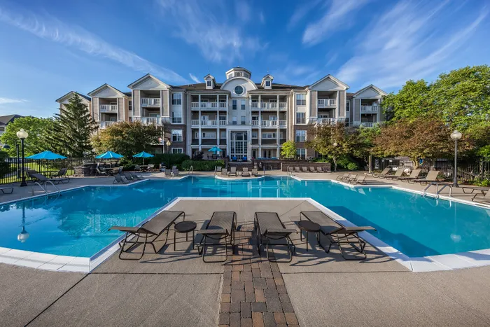 Luxurious apartment community with a sparkling pool and vibrant outdoor seating, surrounded by lush greenery.