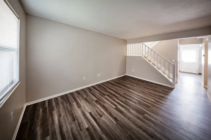 Bright and open modern living room with elegant hardwood floors and a stylish staircase.