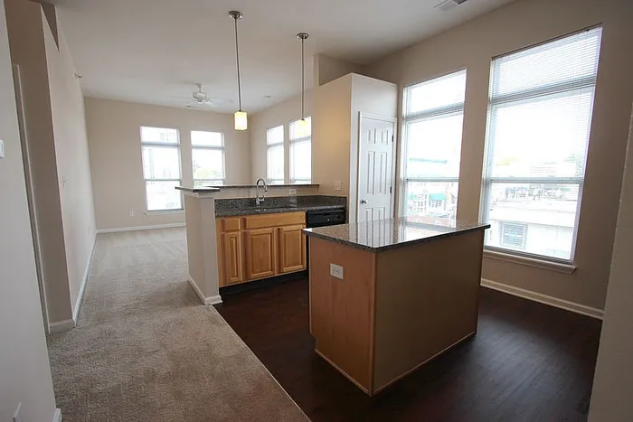 Modern open-concept kitchen with granite countertops, sleek wooden cabinetry, and abundant natural light through large windows.