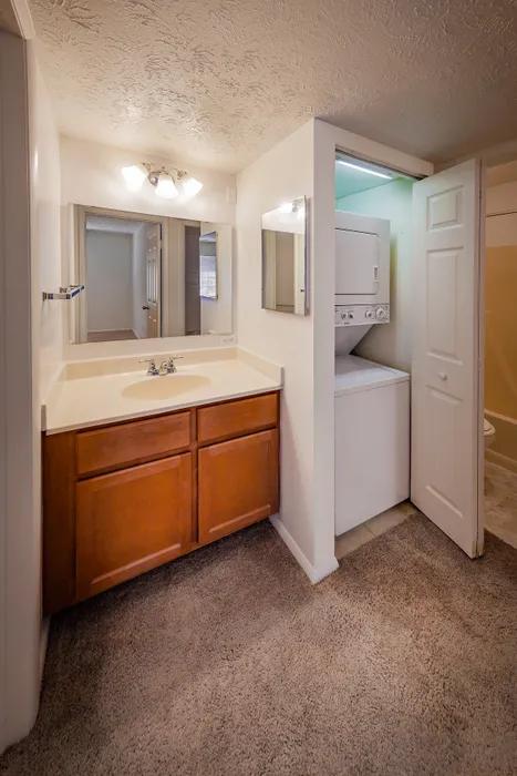 Bright apartment bathroom with elegant vanity, large mirror, and convenient in-unit laundry.