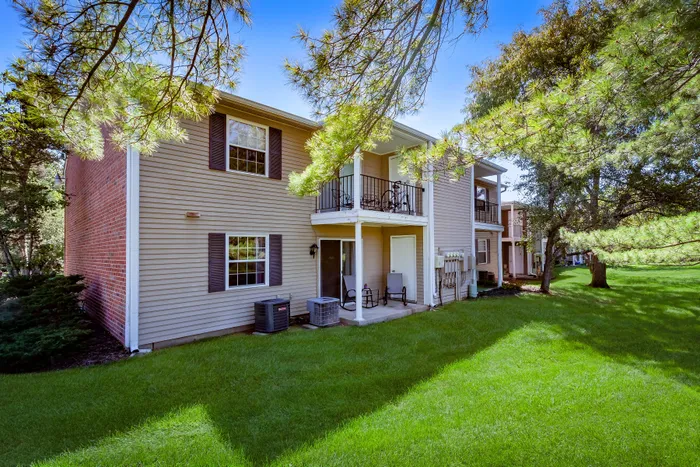 Charming apartment exterior with a private balcony and lush green surroundings.